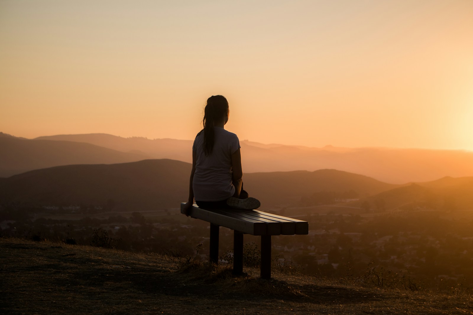 Angebote woman sitting on bench over viewing mountain